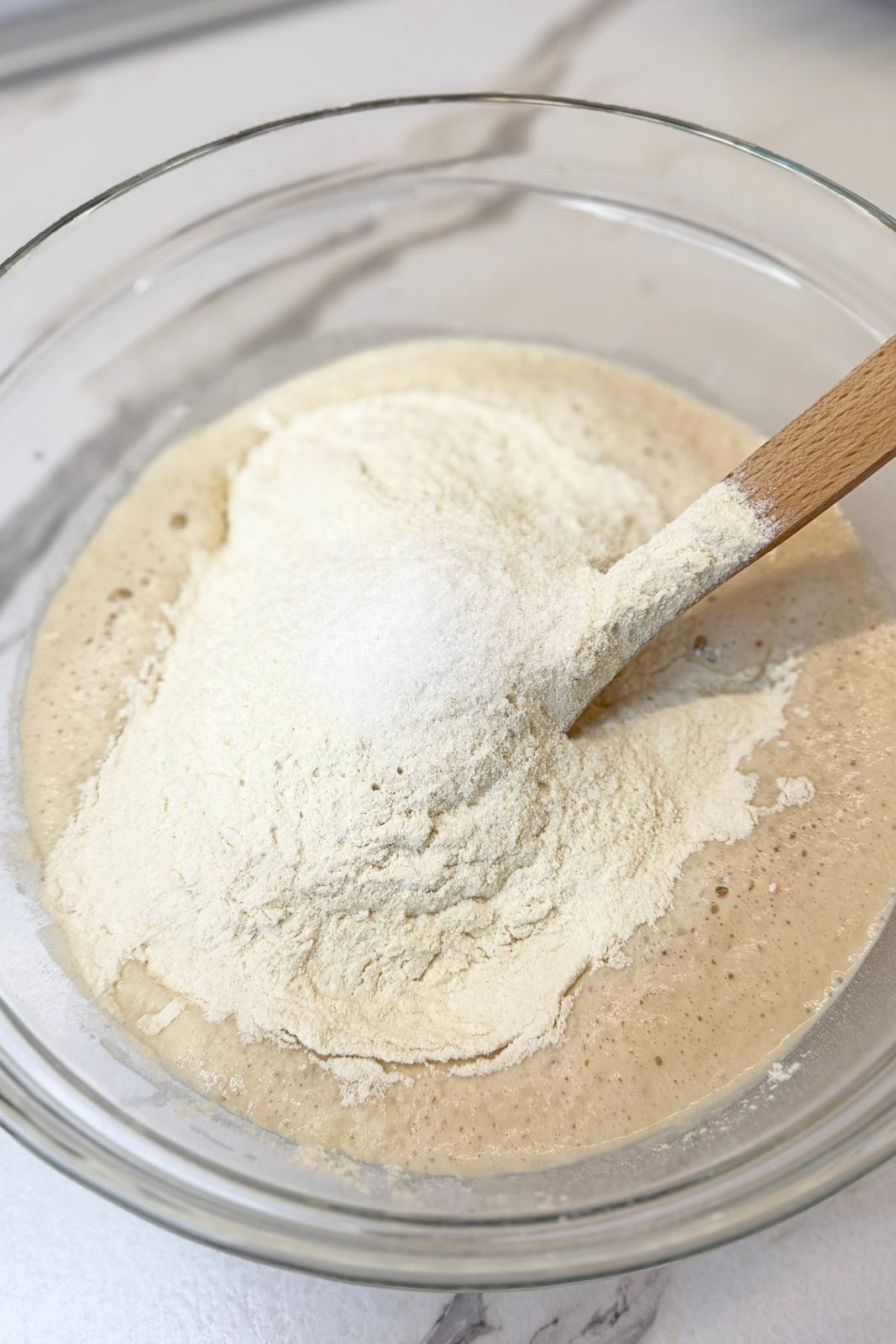 Flour and salt being added to the activated yeast mixture