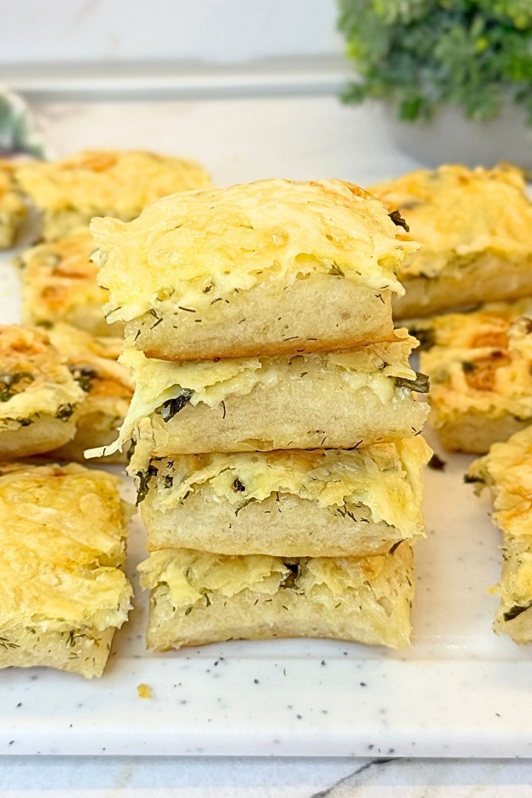 Soft homemade garlic bread squares with melted cheese and fresh herbs