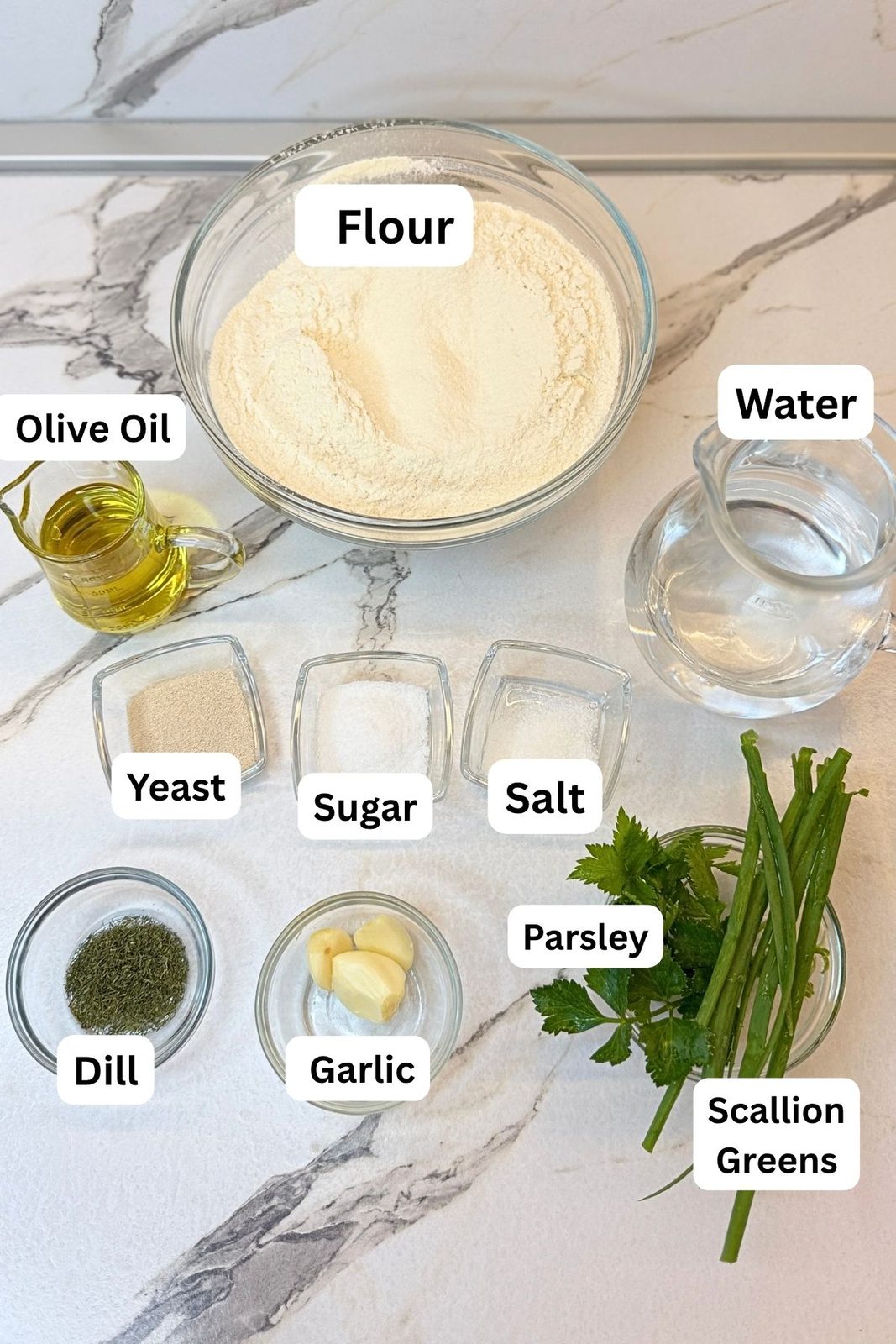 Ingredients for homemade garlic bread including flour, yeast, water, olive oil, garlic, and fresh herbs