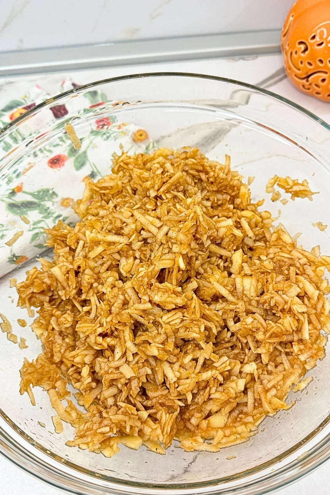 Grated apples mixed with cinnamon and sugar in a glass bowl.
