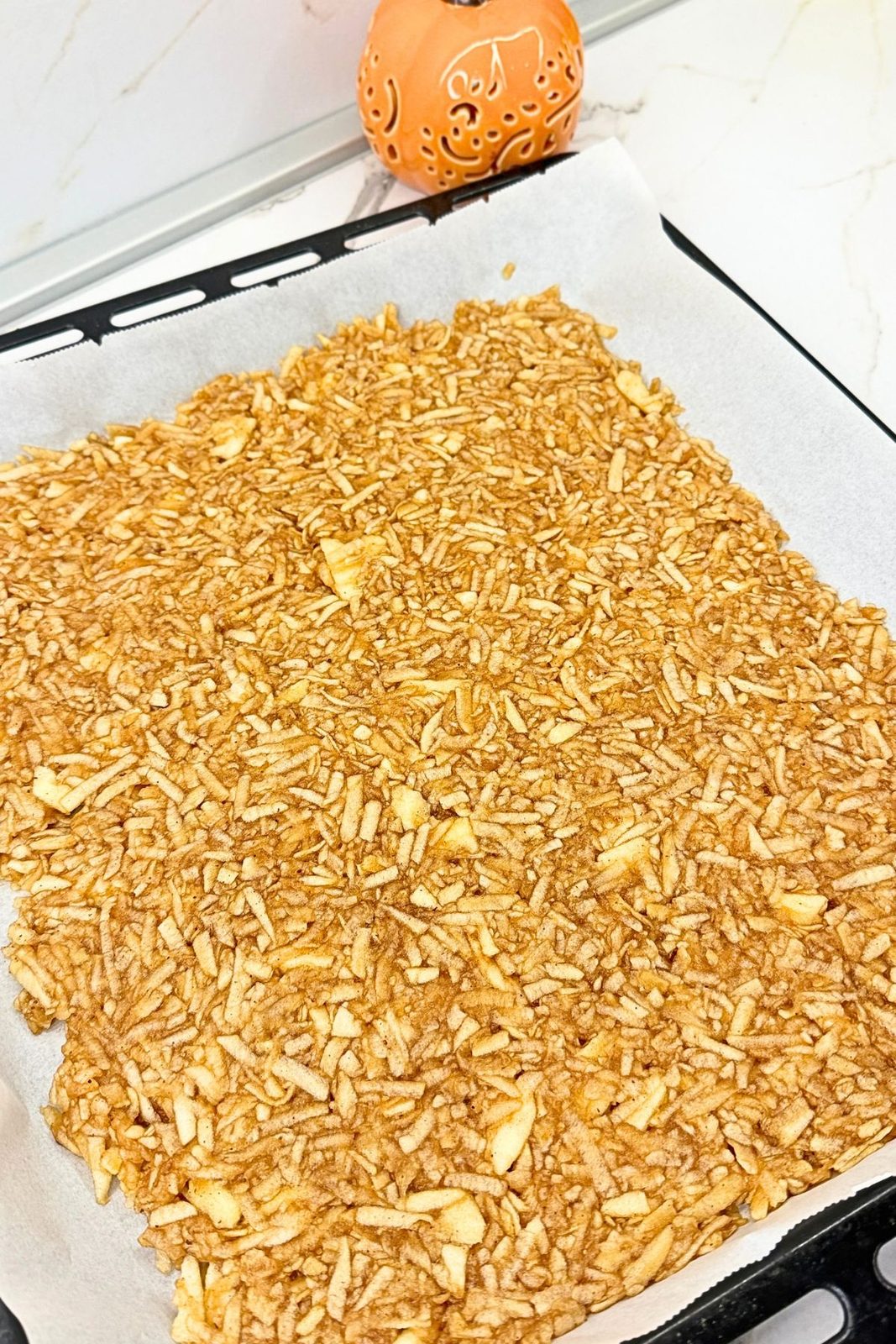 Grated apple filling spread evenly on a parchment-lined baking sheet.
