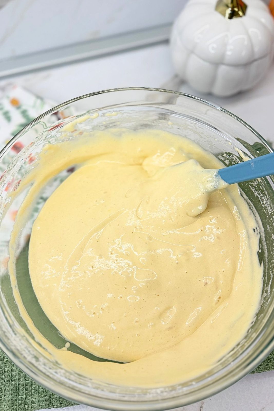 Vanilla sponge cake batter in a glass bowl with a blue spatula.