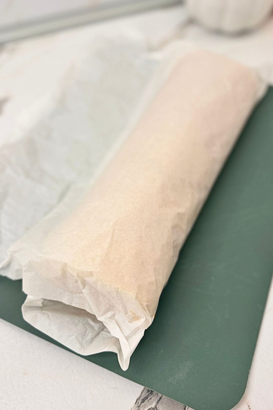 Apple cinnamon cake roll wrapped in parchment paper and left to cool.