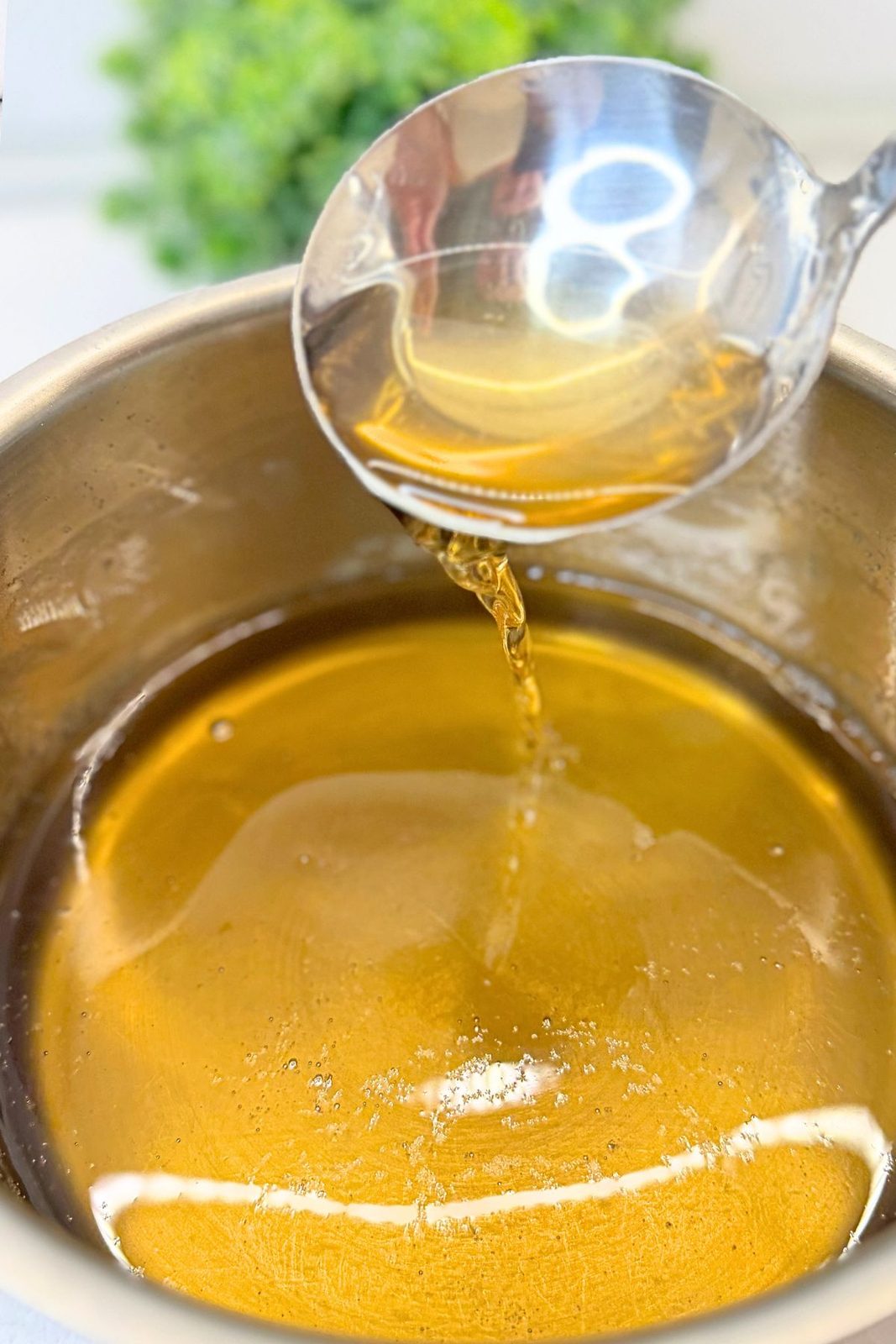 Vanilla sugar syrup in a saucepan with a ladle, ready to pour over baked apple phyllo rolls.