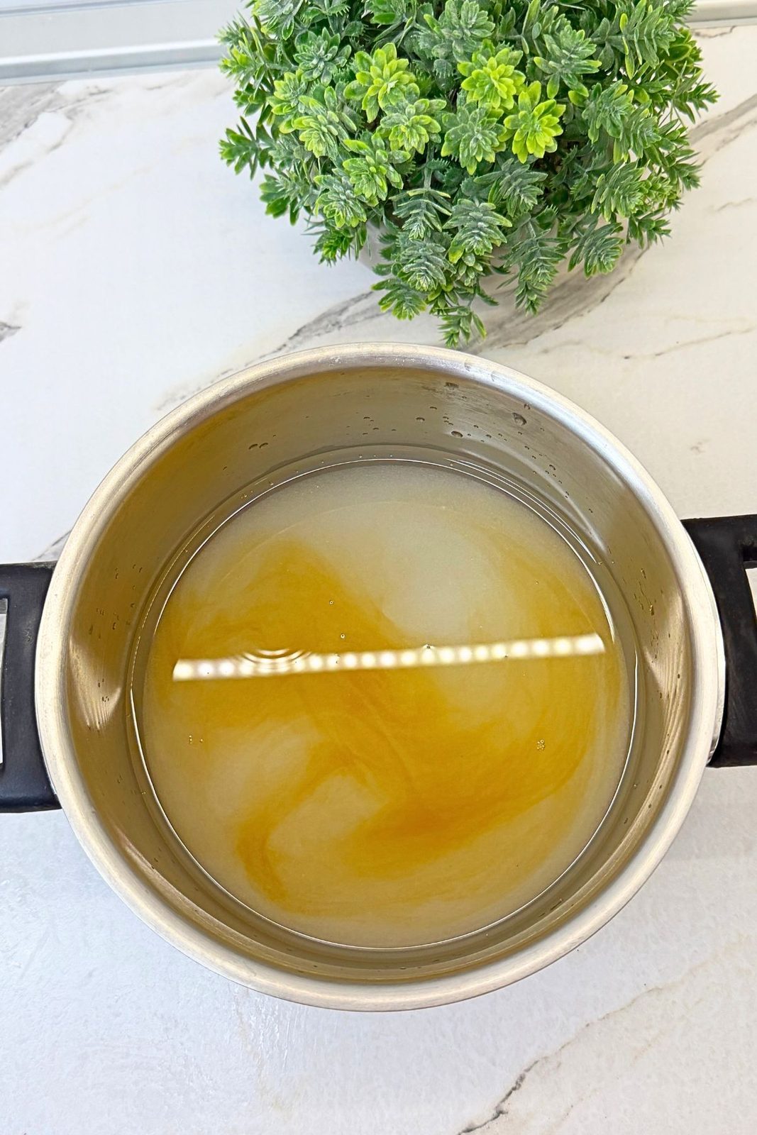 Vanilla sugar syrup in a saucepan with a ladle, ready to pour over baked apple phyllo rolls.