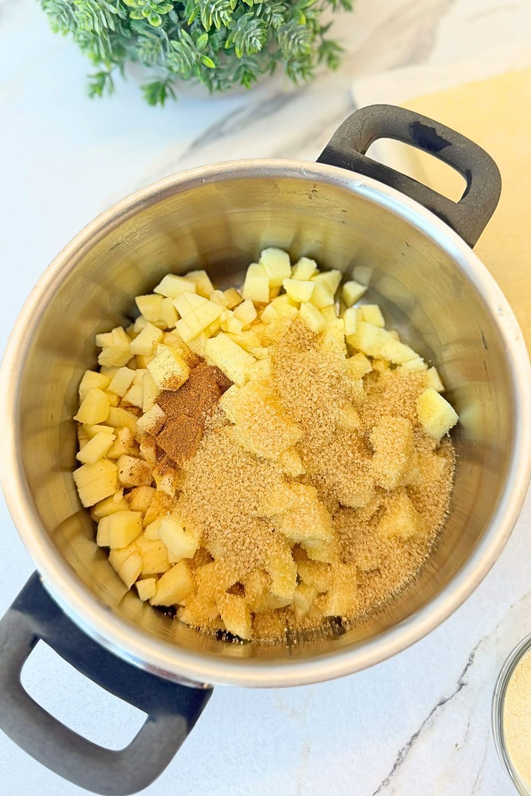Diced apples with brown sugar and cinnamon in a saucepan before cooking the turnover filling.