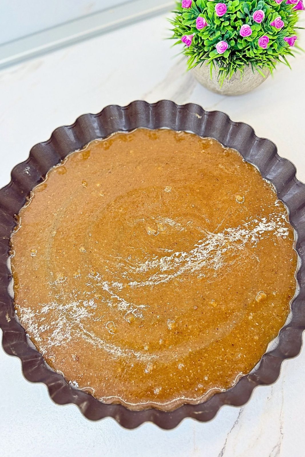 Caramel topping spread across the bottom of a round fluted baking pan.