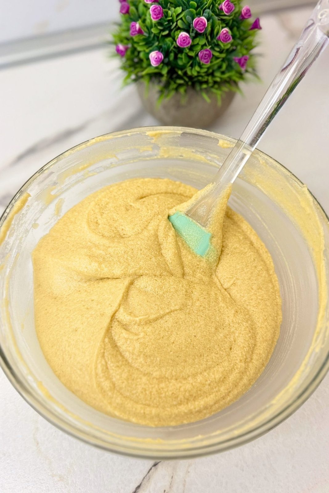 Apple upside down cake batter in a glass bowl with a silicone spatula.