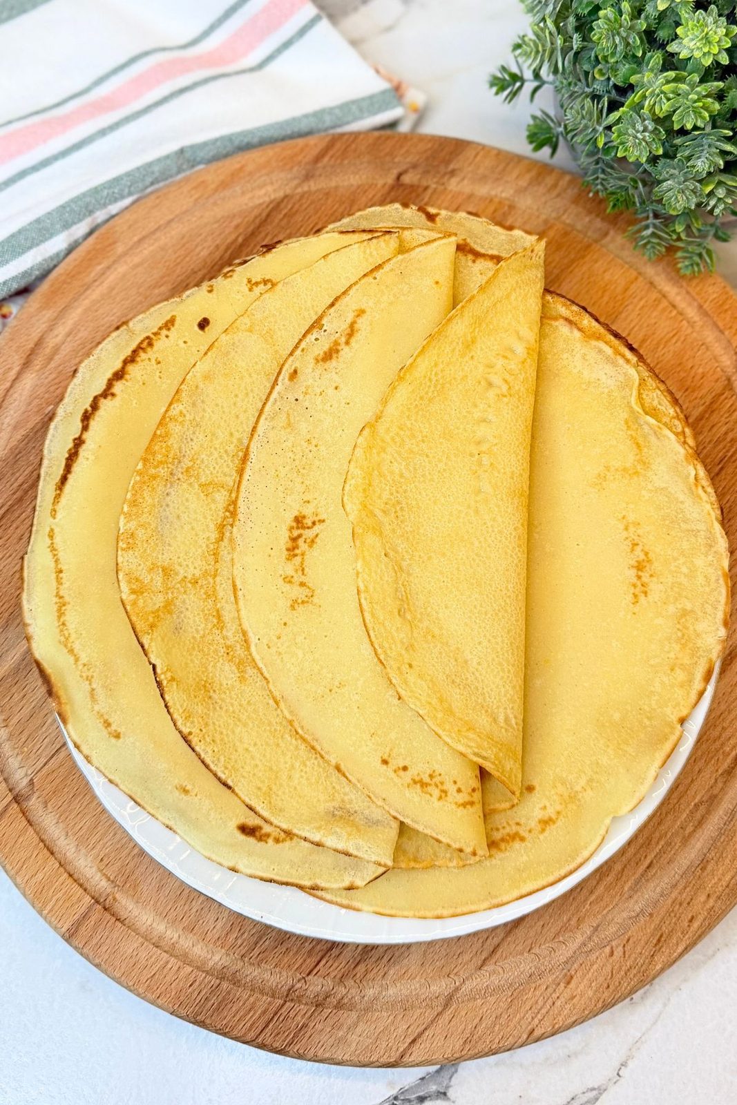 Stack of freshly cooked thin homemade crepes arranged on a plate