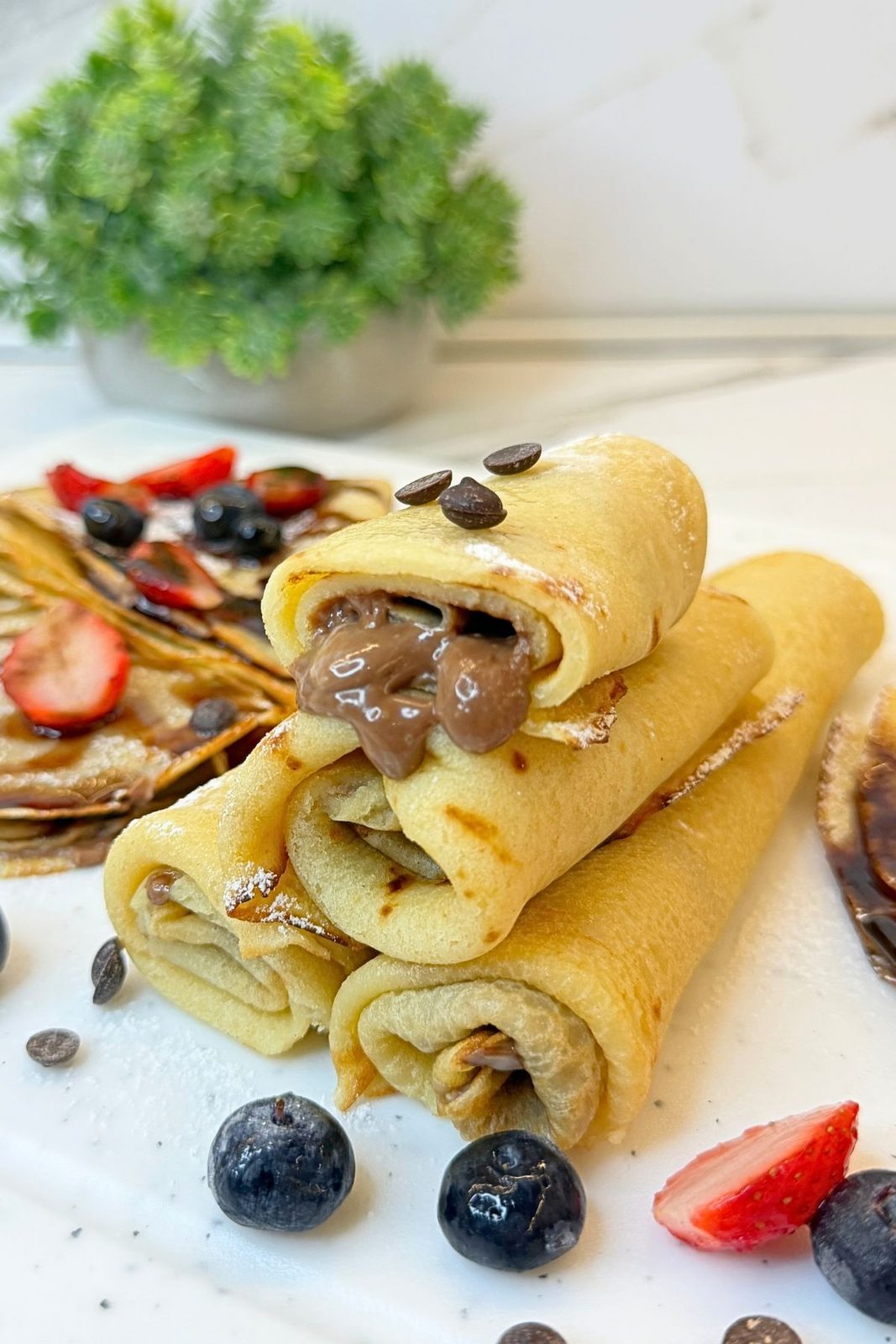 Thin homemade crepes filled with Nutella and served with fresh strawberries and blueberries