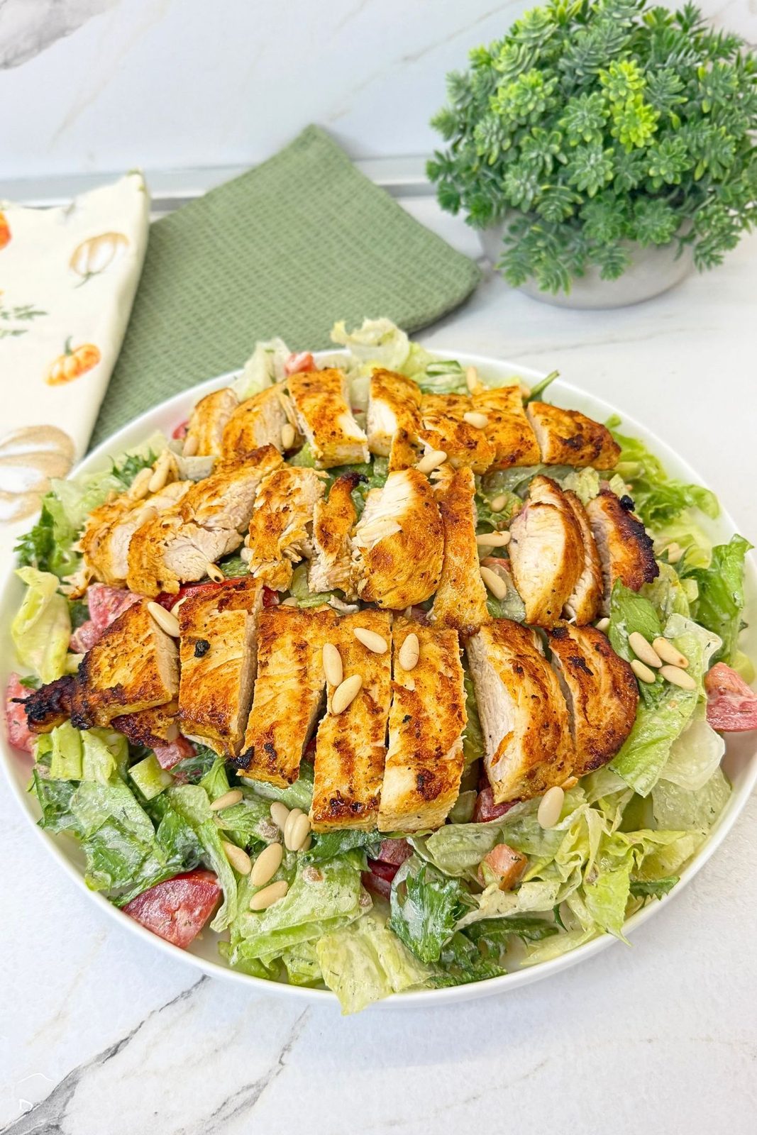 Easy grilled chicken salad with creamy dressing, sliced chicken breast, fresh vegetables, and pine nuts.