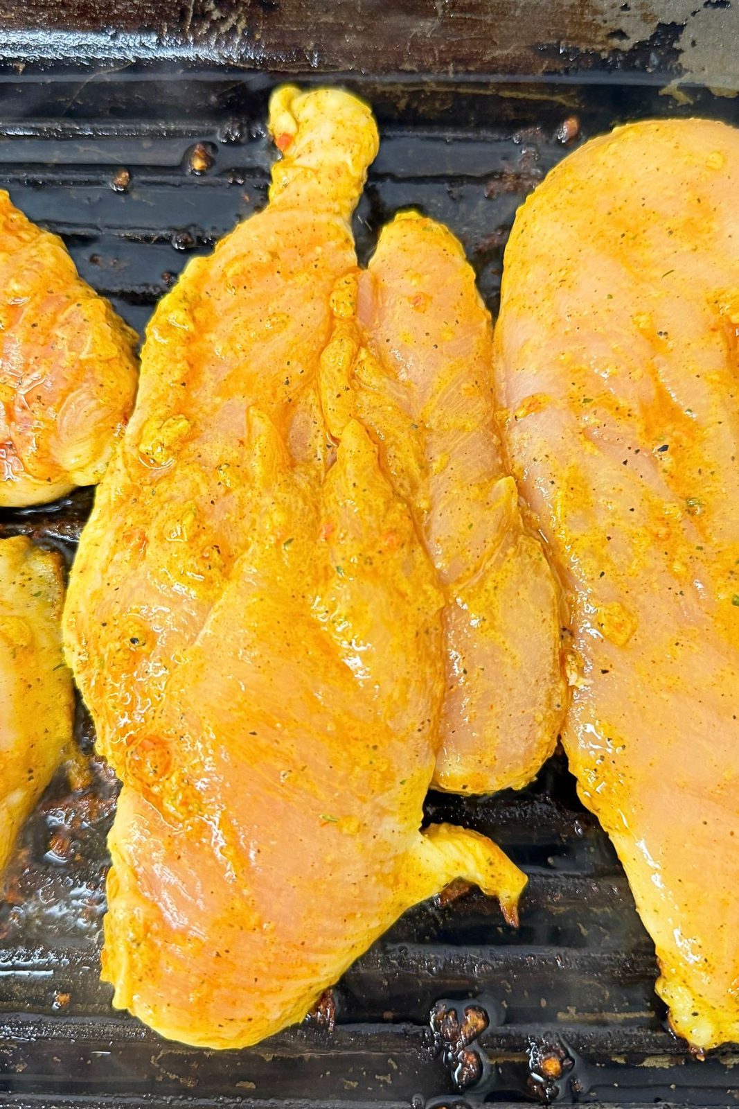 Mustard-seasoned chicken breast cutlets cooking in a hot grill pan.