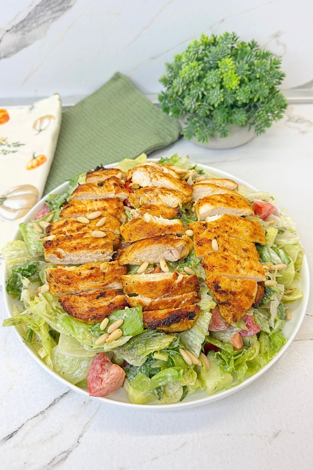 Easy Grilled Chicken Salad with creamy dressing, sliced chicken breast, fresh vegetables, and pine nuts.