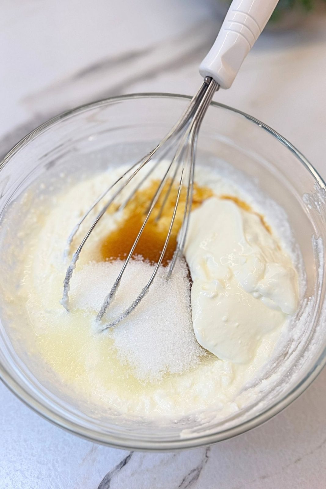 Cream cheese, sugar, sour cream, and vanilla in a bowl for cheesecake filling