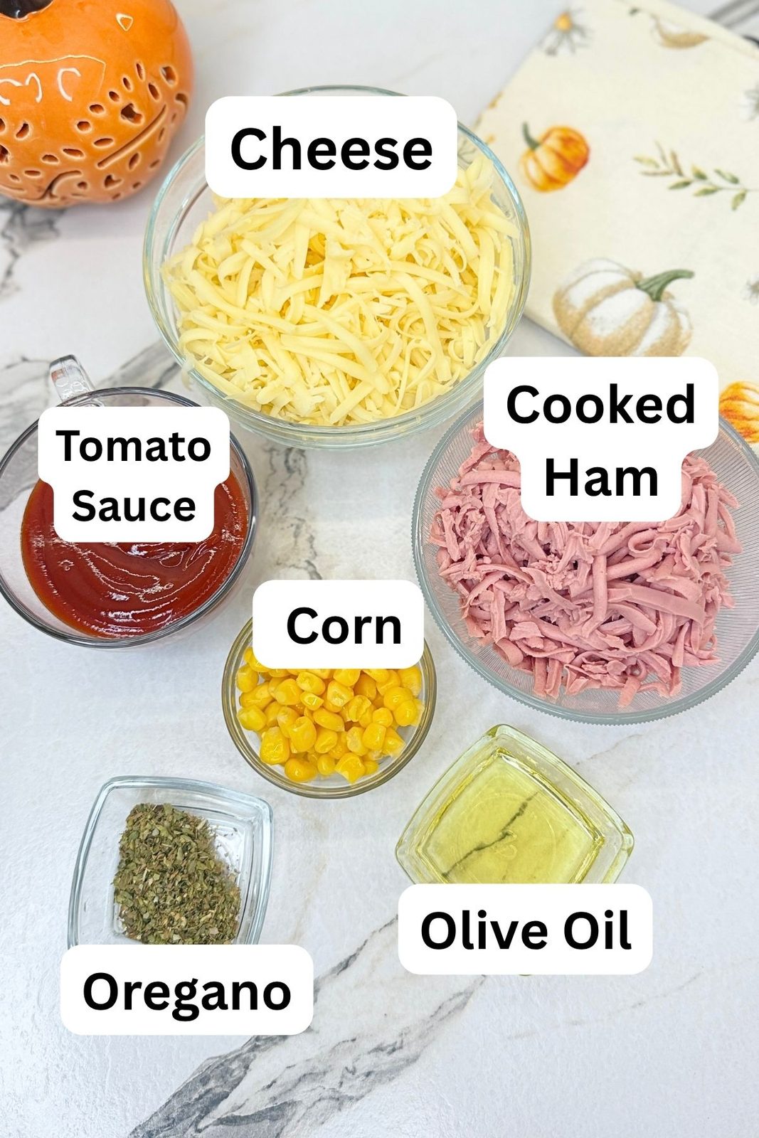 Pizza ring toppings including shredded cheese, cooked ham, tomato sauce, corn, oregano, and olive oil