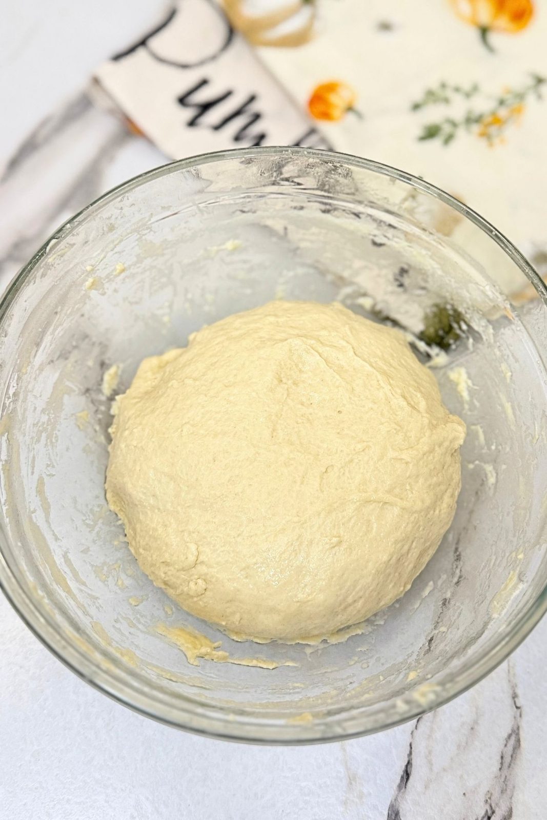 Soft homemade pizza dough in a glass bowl before rising