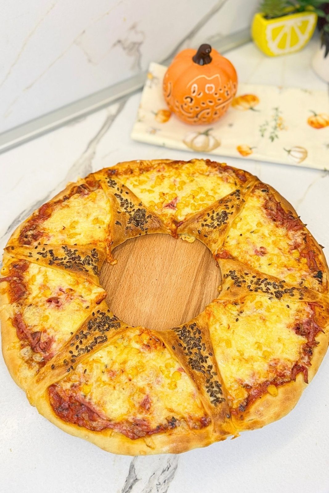 Homemade pizza ring recipe with ham, melted cheese, corn, and seeded pizza dough