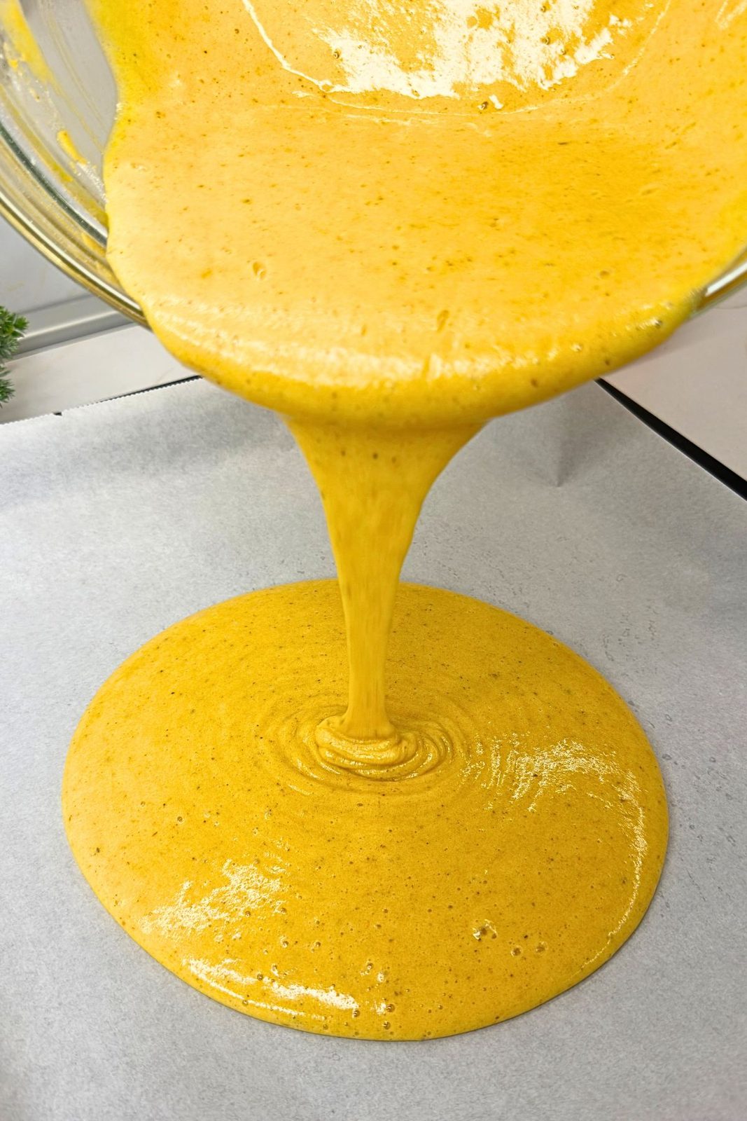 Pumpkin batter spread evenly in a parchment-lined jelly roll pan.