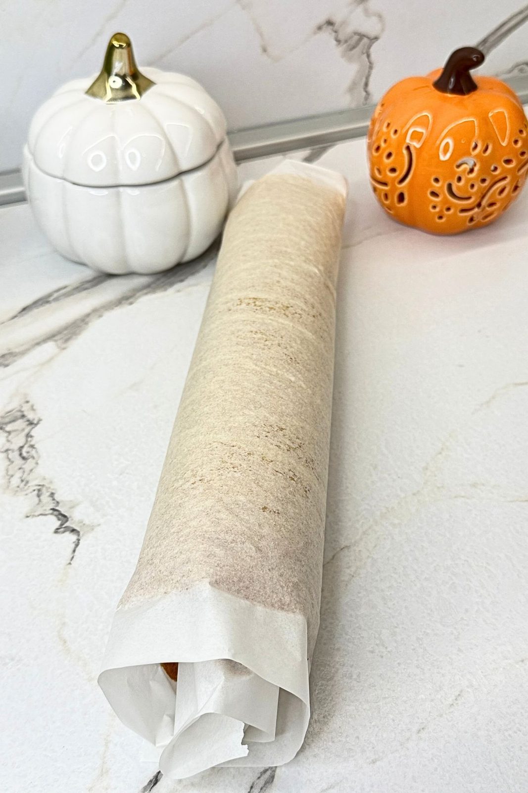 Warm pumpkin sponge rolled with parchment paper to cool.