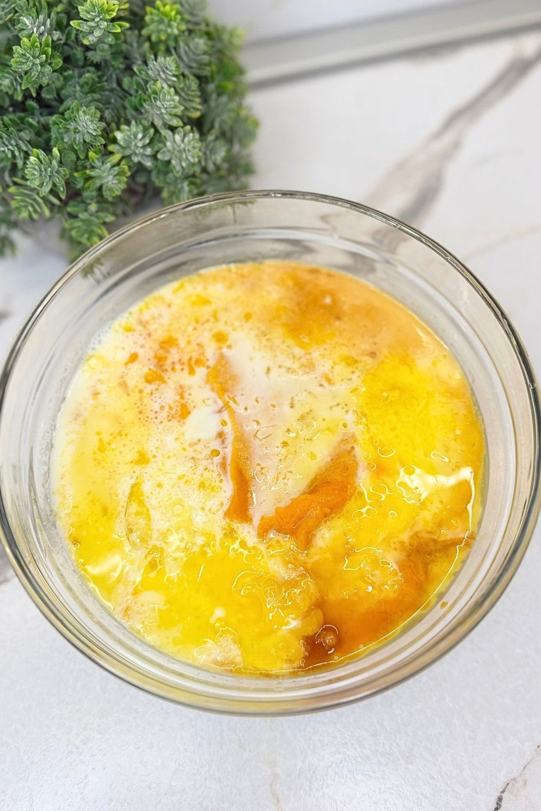 Pumpkin purée, eggs, milk, and melted butter in a glass bowl before mixing the pancake batter.