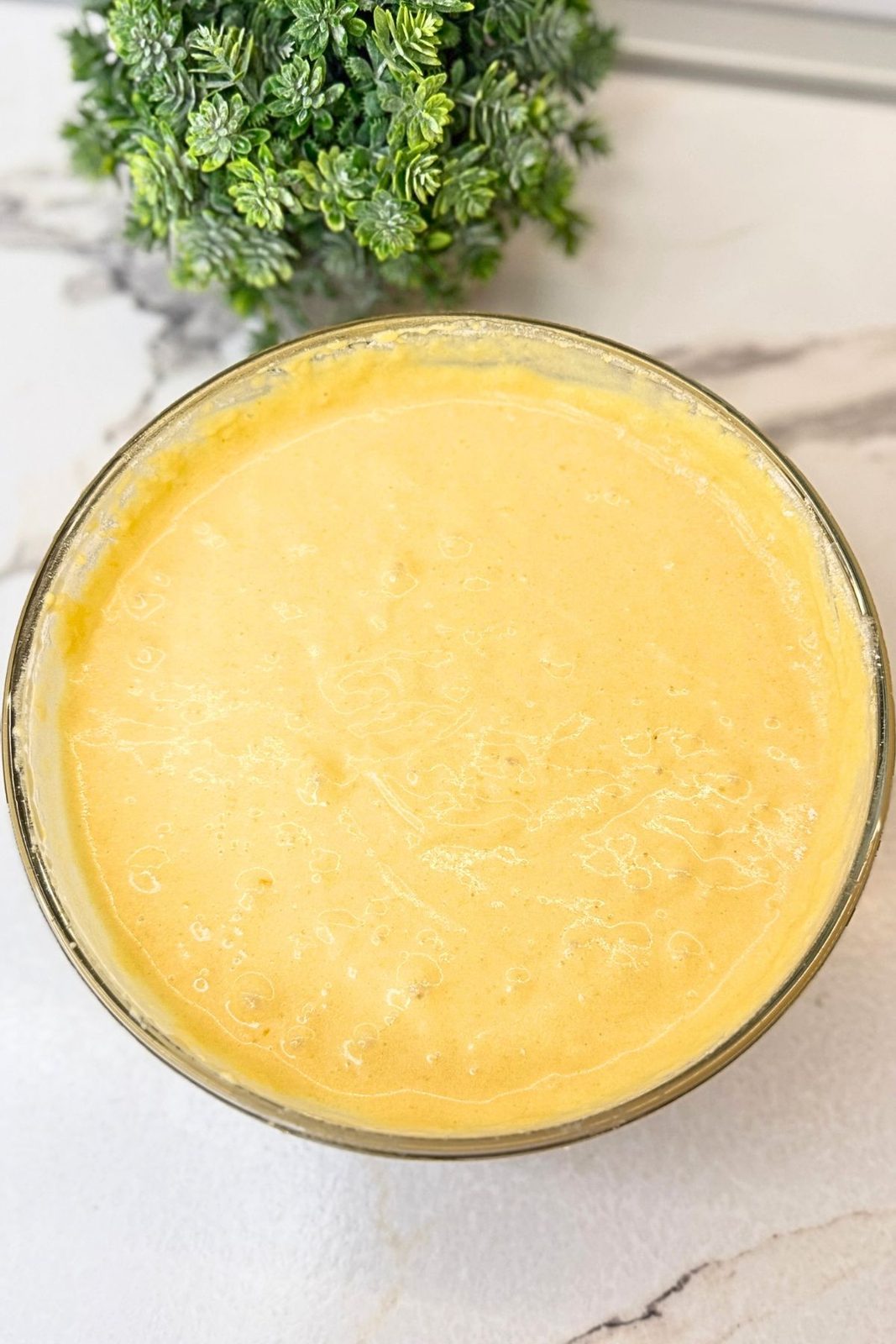 Prepared pumpkin pancake batter resting in a glass mixing bowl before cooking.