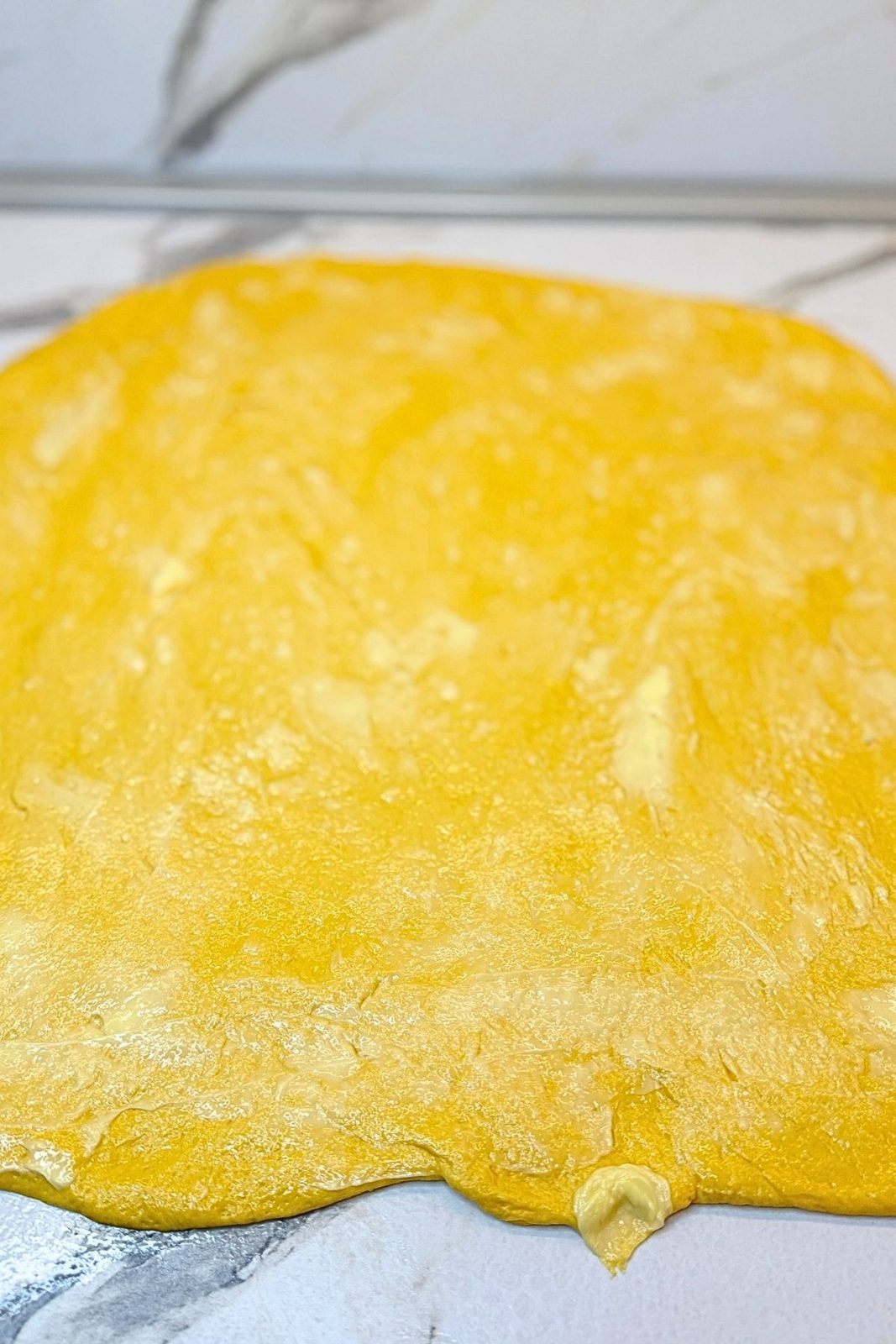 Pumpkin dough stretched into a rectangle and spread with softened butter