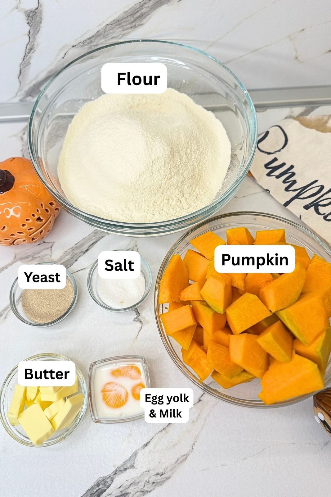 Ingredients for Swirled Pumpkin Dinner Rolls including fresh pumpkin, flour, yeast, butter, salt, egg yolk, and milk