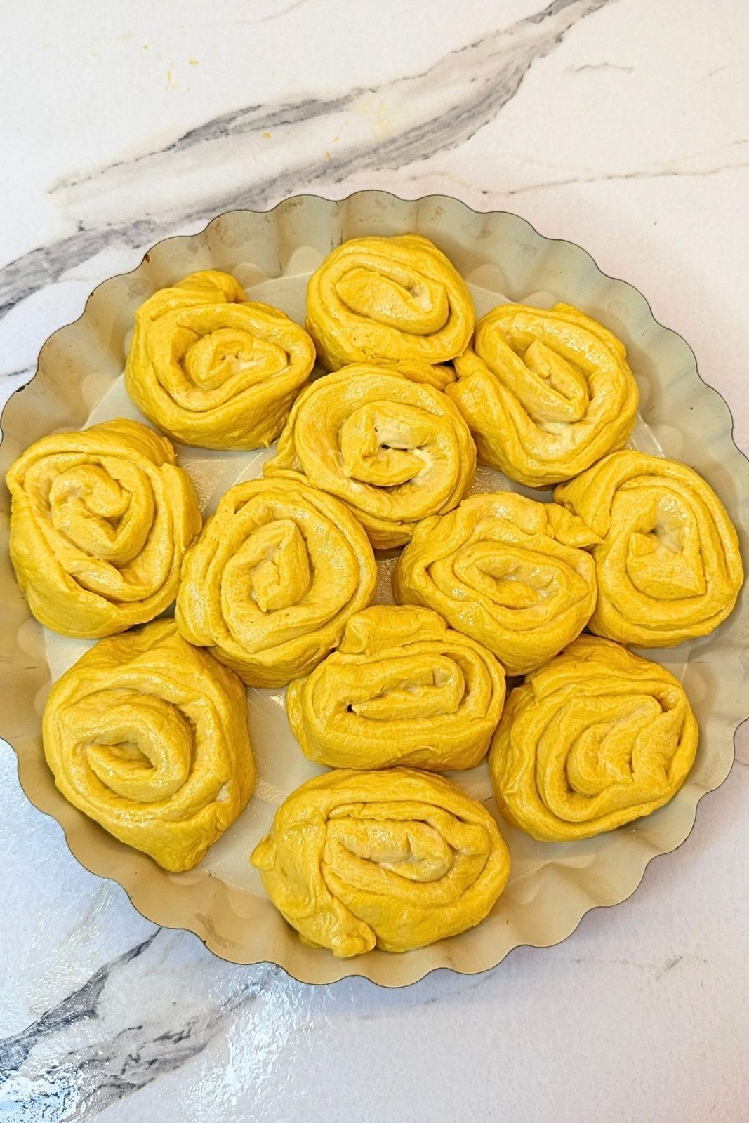 Swirled Pumpkin Dinner Rolls risen in a greased round baking pan