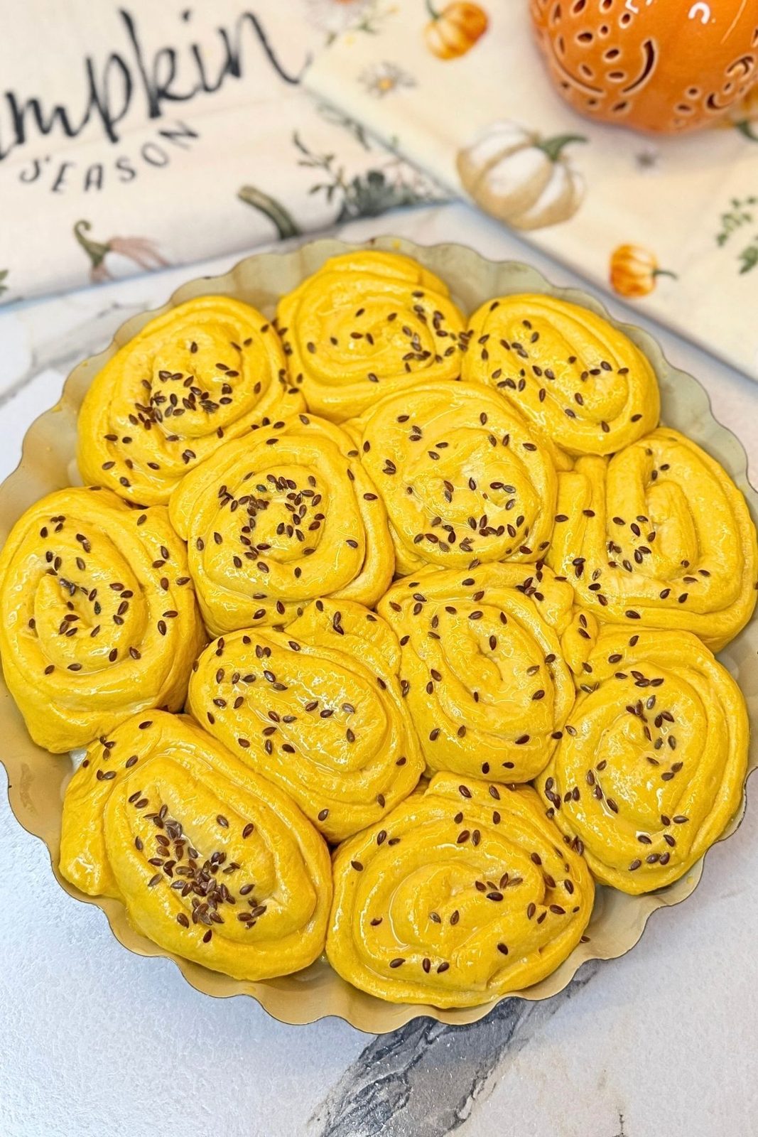 Unbaked Swirled Pumpkin Dinner Rolls topped with flax seeds before baking