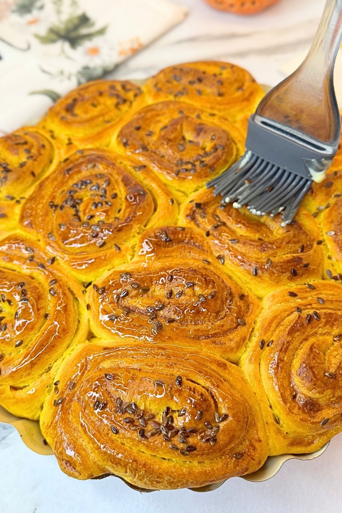 Golden Swirled Pumpkin Dinner Rolls topped with flax seeds in a round baking pan