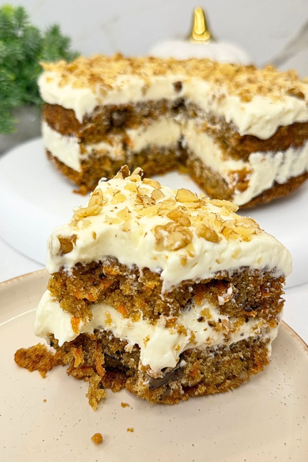 Partially eaten slice of carrot cake with cream cheese frosting and chopped walnuts, showing the moist crumb and creamy layers.