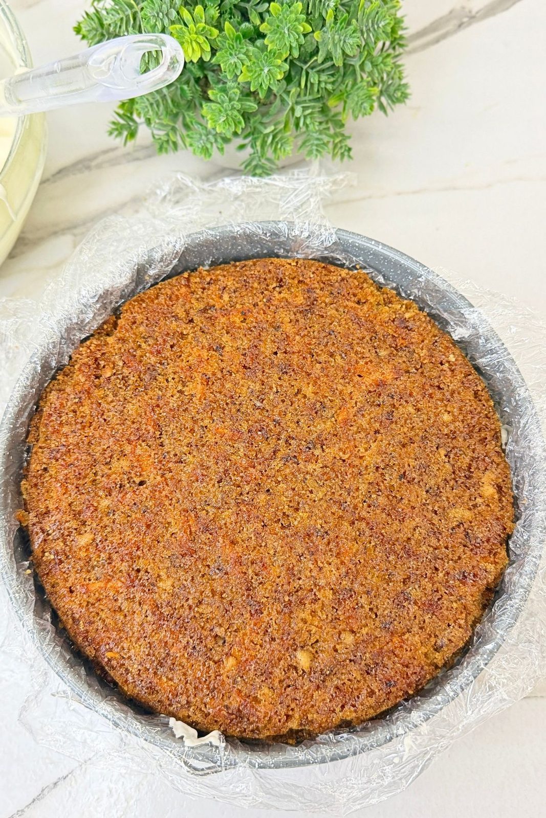 Second carrot cake layer placed over the cream cheese frosting in the lined pan.