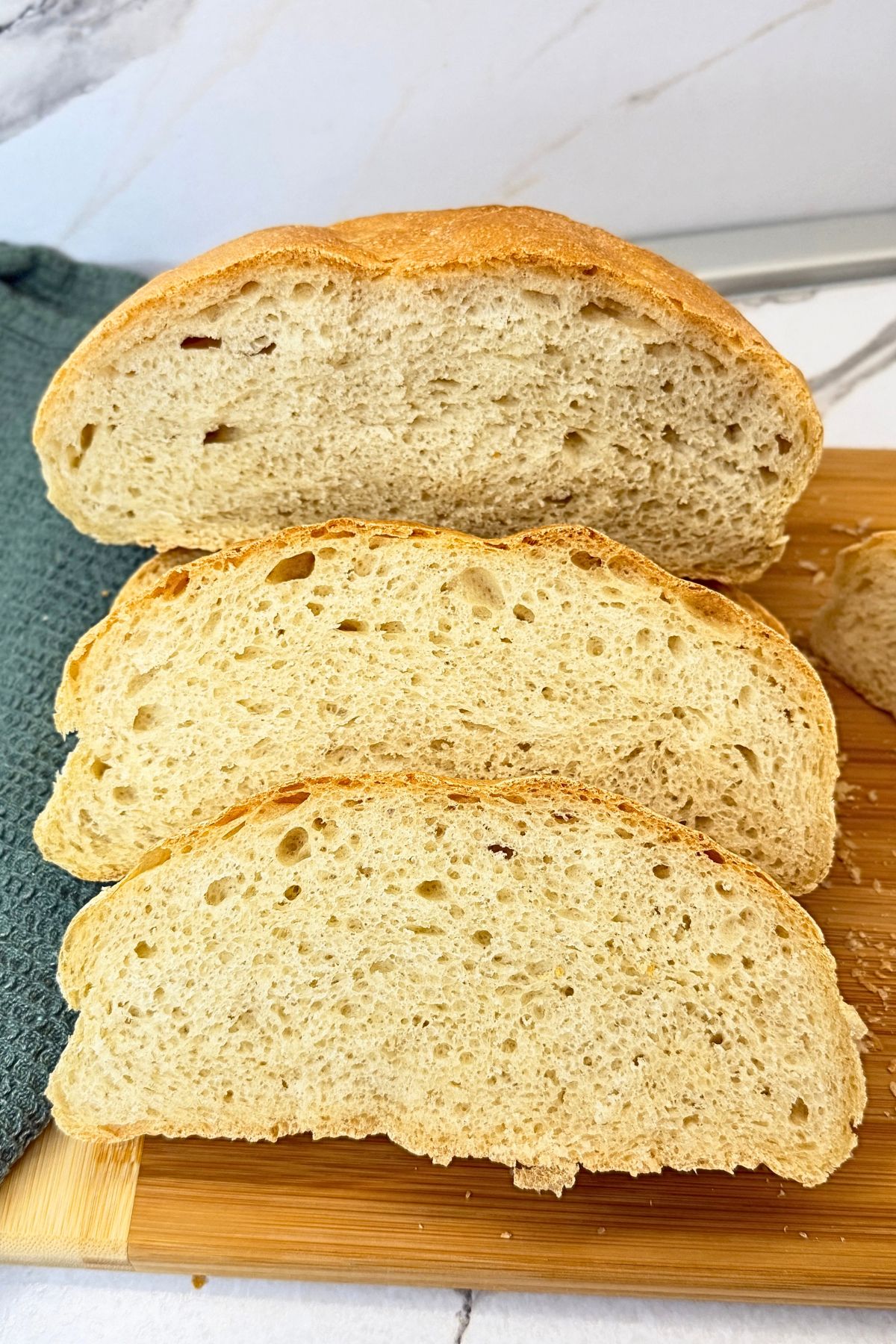 Homemade bread with a golden crust and soft, fluffy interior, sliced on a wooden cutting board.