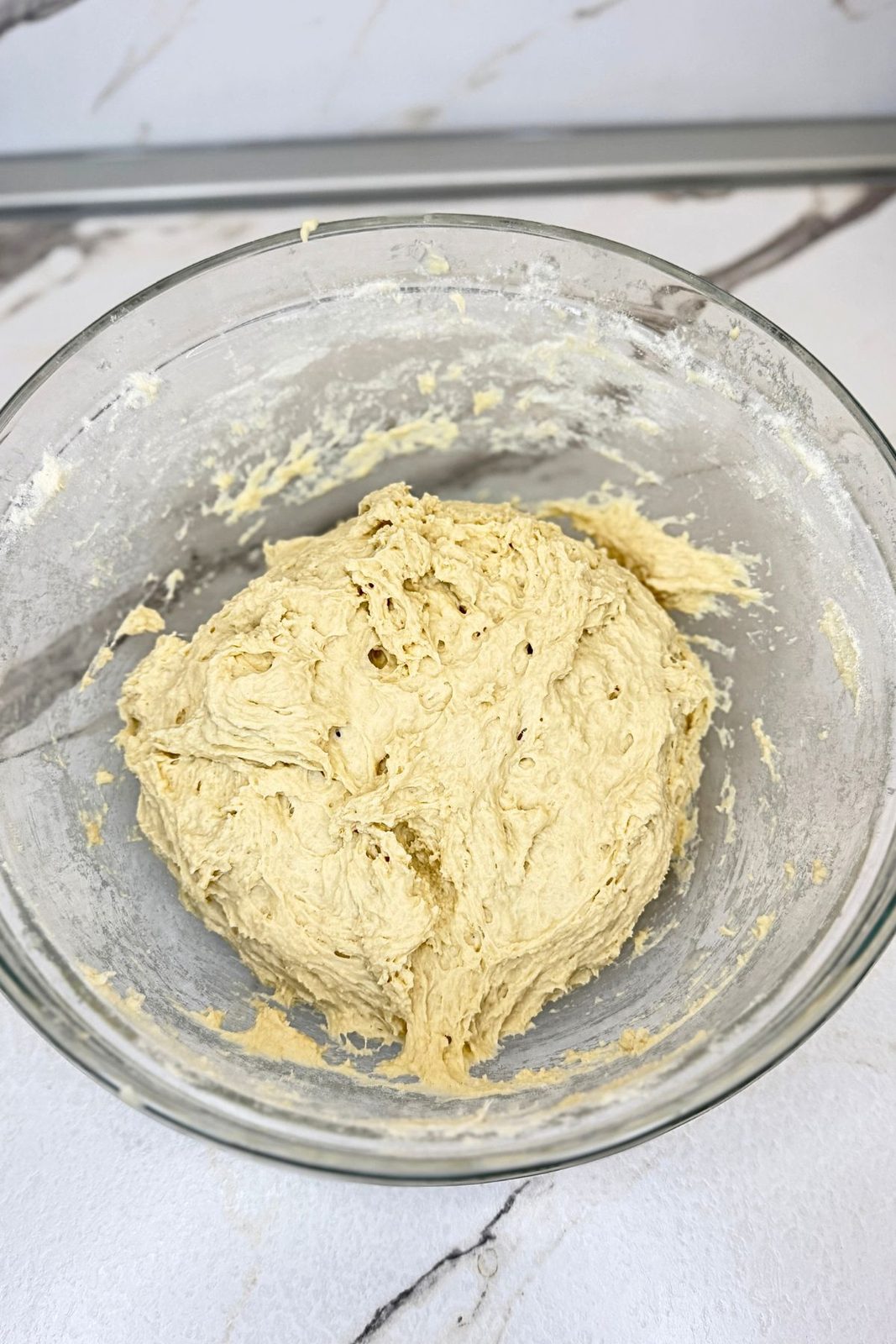 Soft homemade bread dough mixed in a glass bowl before the first rise.