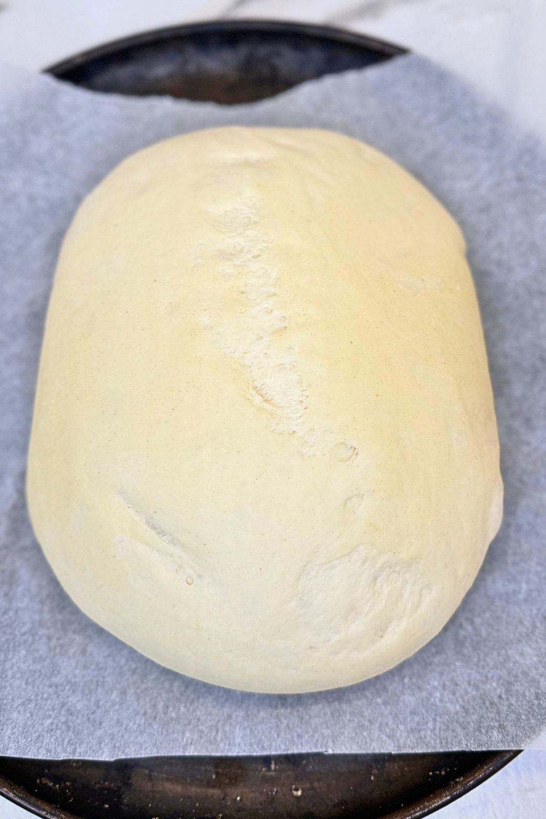 Shaped bread dough on a parchment-lined baking sheet before baking.