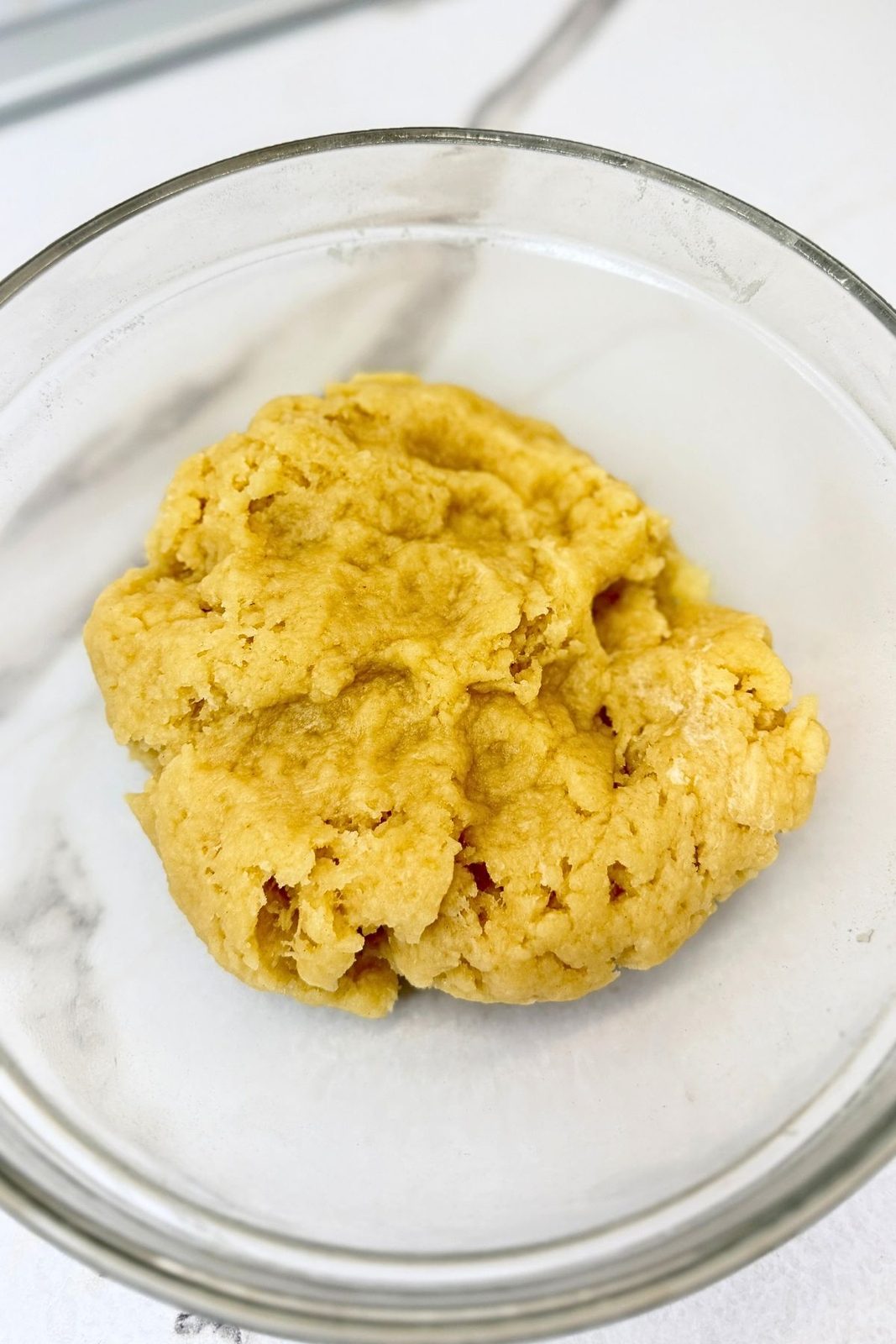 Dough for jam filled crescent cookies in a glass mixing bowl, ready to rest before rolling.