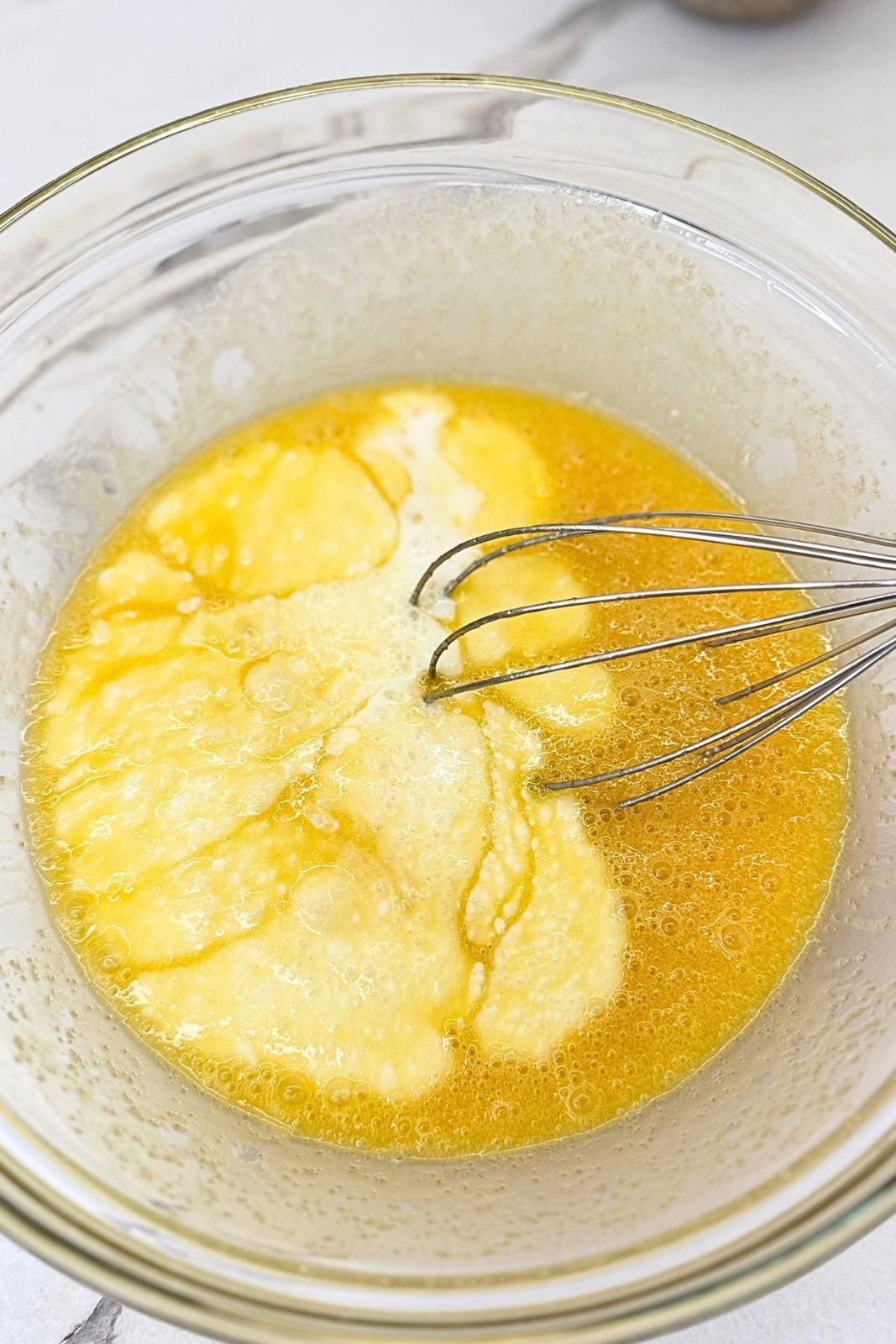 Wet ingredients for marble loaf cake in a glass bowl, ready to whisk together.