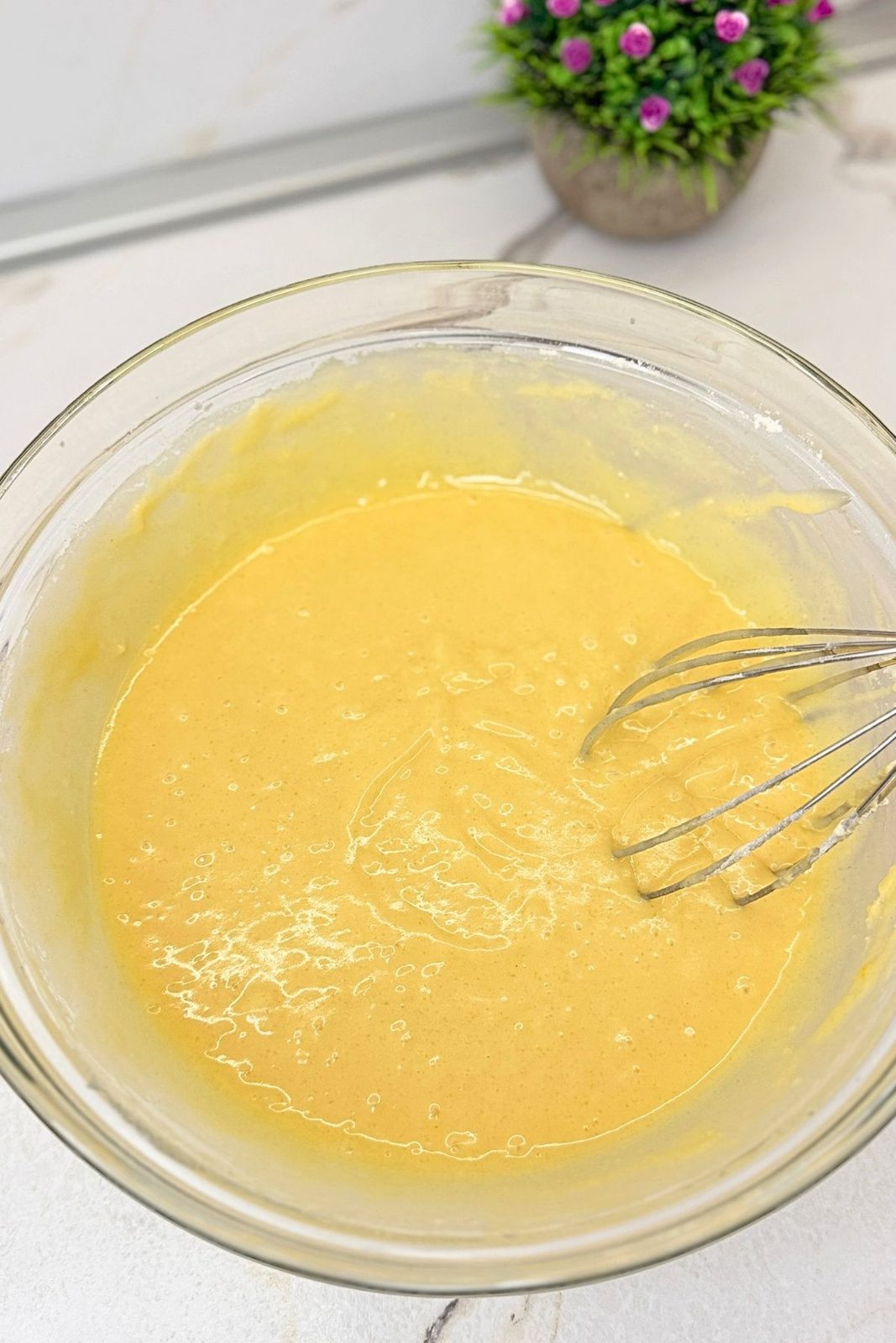 Smooth vanilla batter for marble loaf cake in a glass mixing bowl with a whisk.