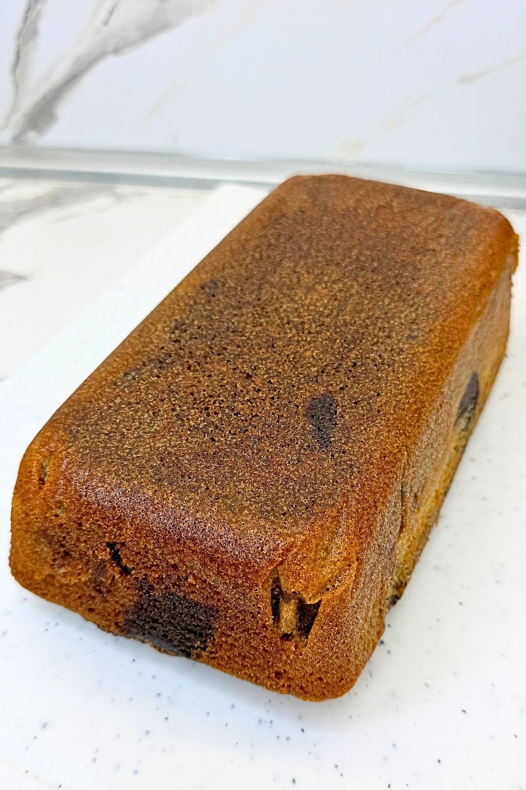 Baked marble loaf cake removed from the pan and turned out onto a white serving board before glazing.