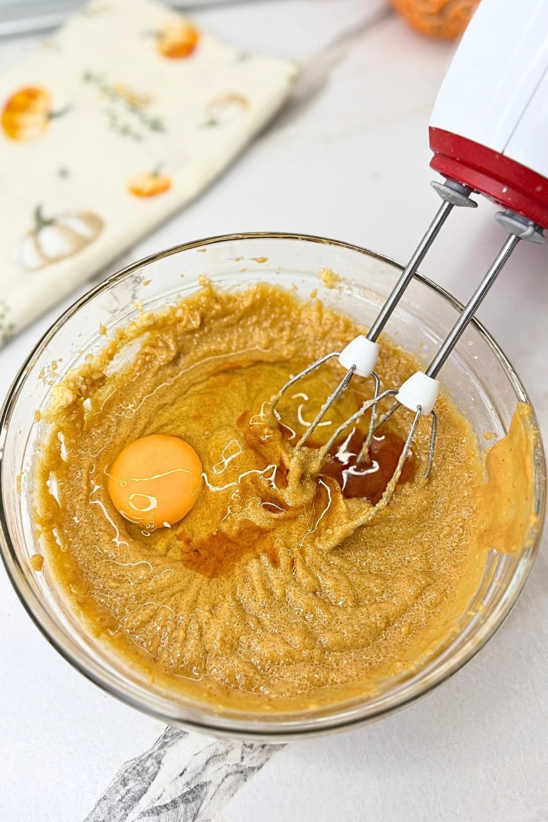 Egg and vanilla extract added to the peanut butter mixture in a glass bowl.