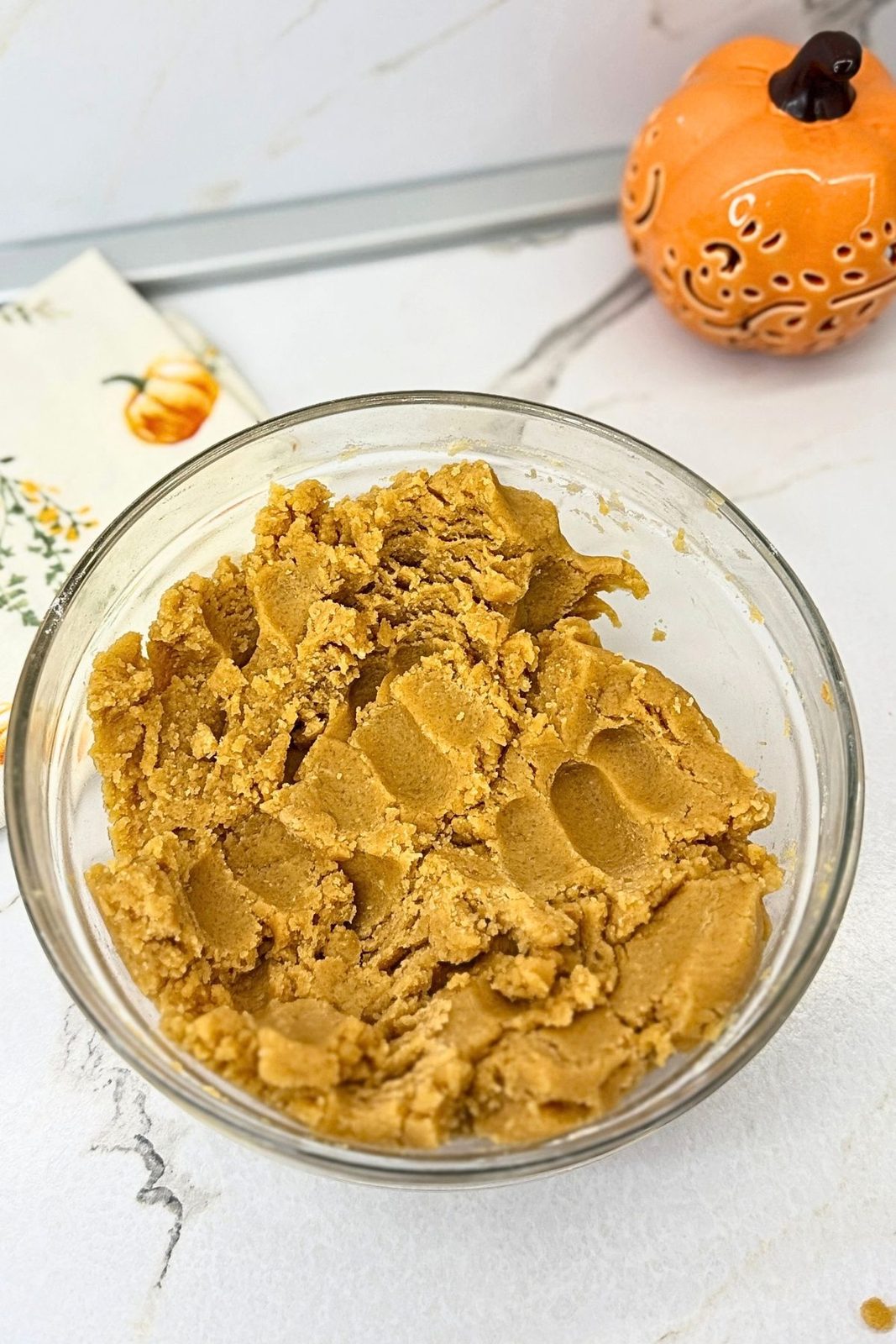 Thick peanut butter cookie dough in a glass mixing bowl, ready to shape.