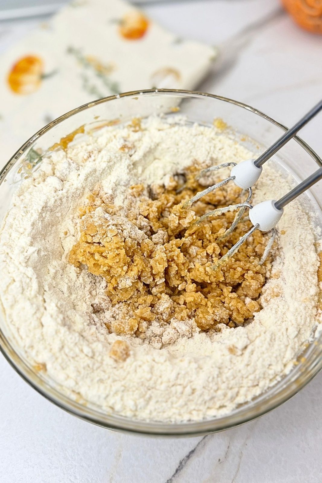 Flour mixture being mixed into peanut butter cookie dough with a hand mixer.
