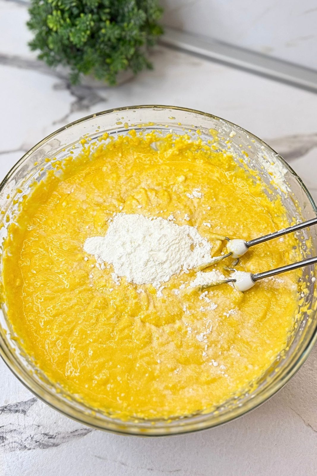 Cornstarch added to the pumpkin cheesecake batter in a glass mixing bowl.