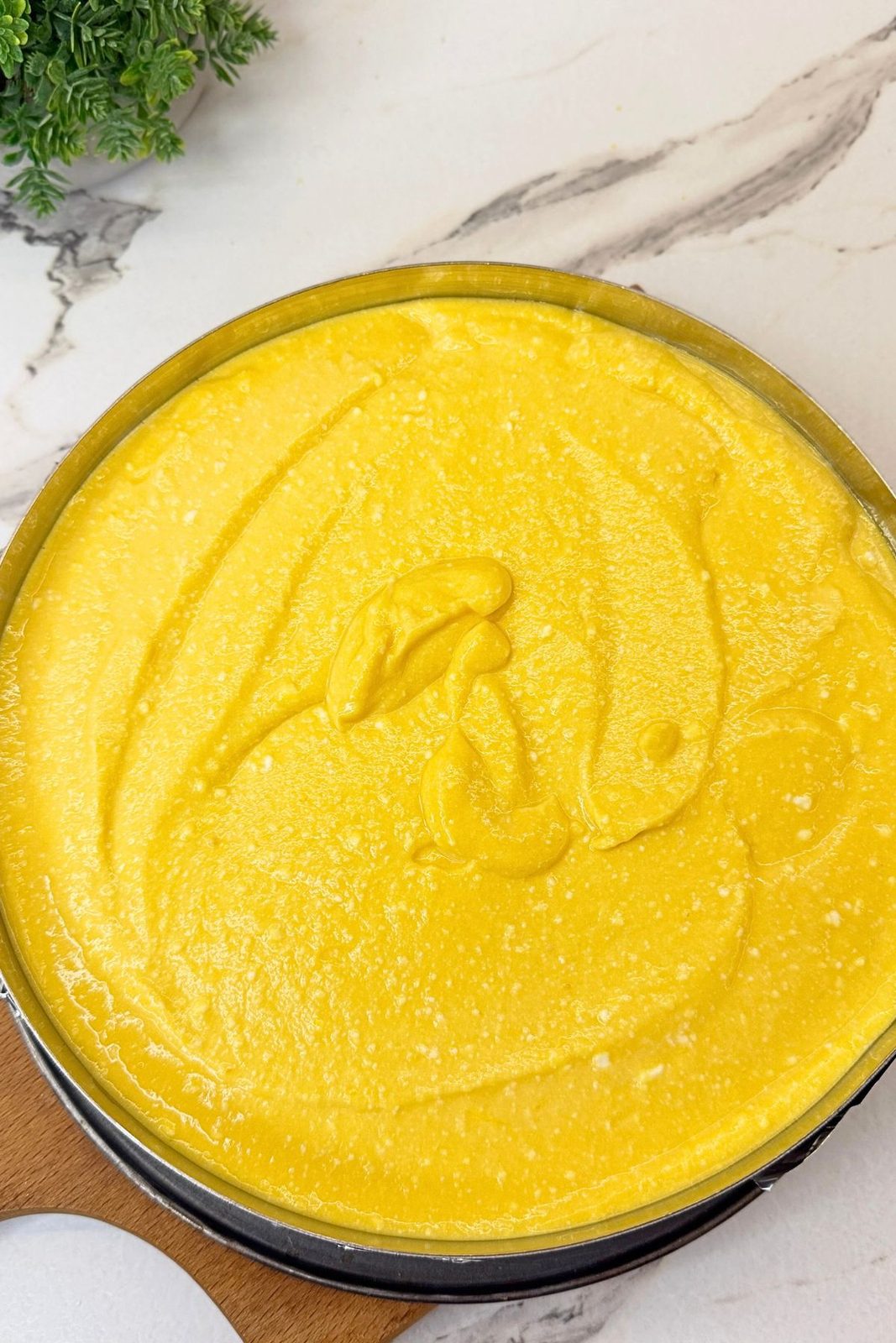 Pumpkin cheesecake filling spread over the graham cracker crust in a springform pan before baking.