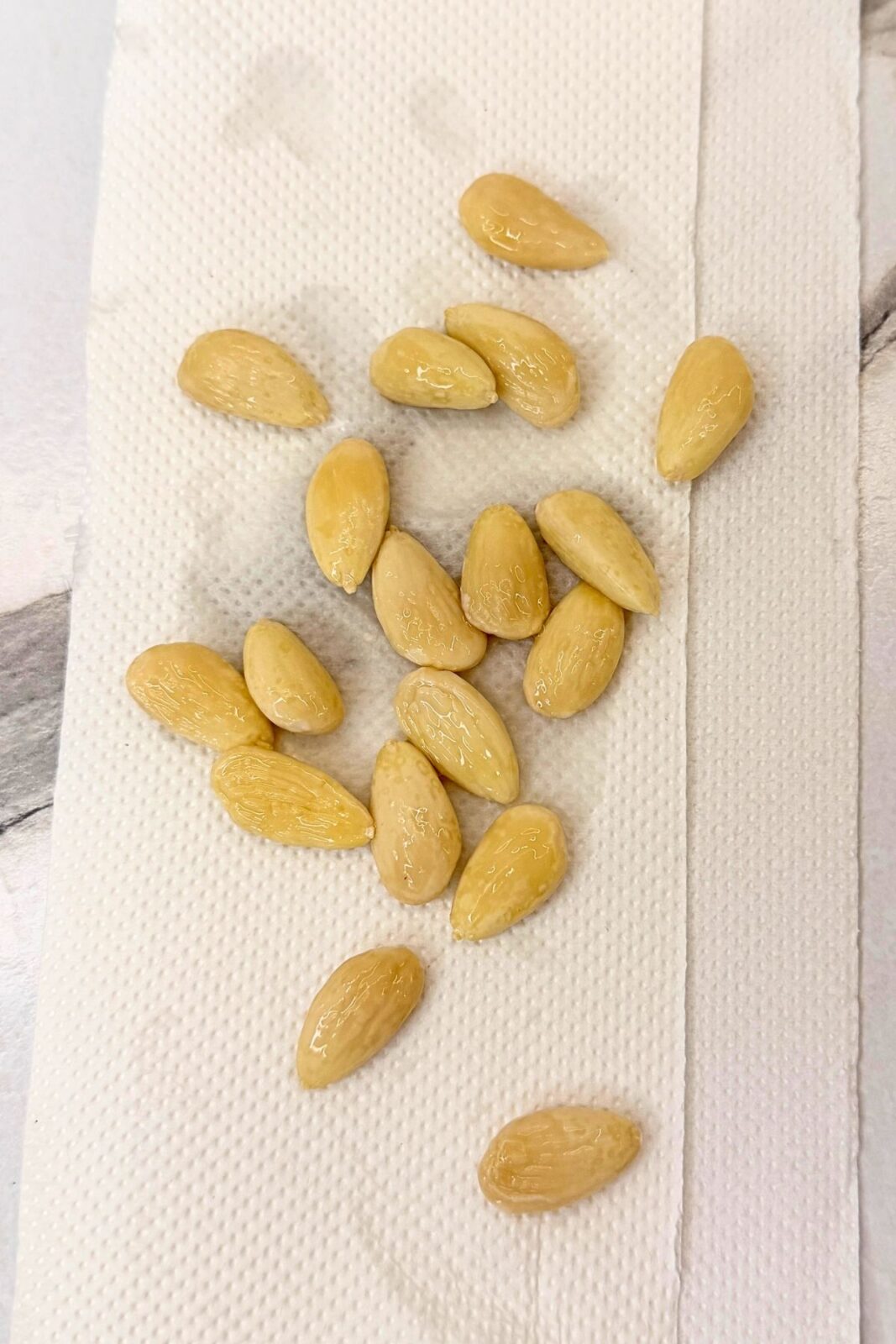 Peeled blanched almonds spread in a single layer on a paper towel to dry.