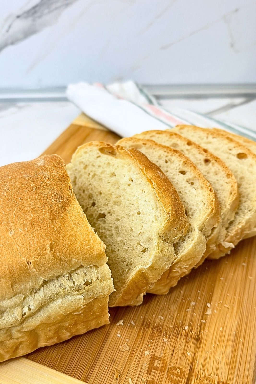 Homemade sandwich bread loaf with overlapping slices on a wooden cutting board, showing its golden crust and soft crumb.