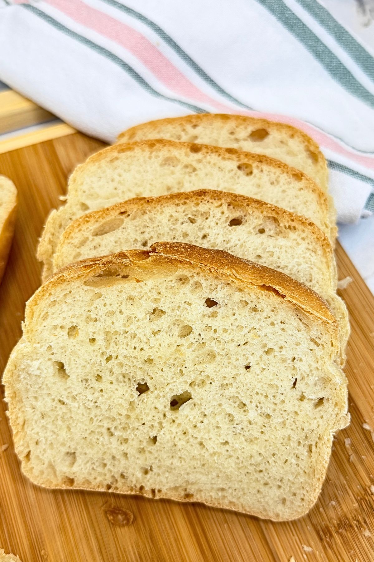 Homemade sandwich bread with a golden crust and soft interior, sliced on a wooden cutting board.
