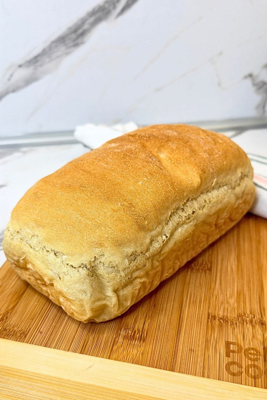 Golden homemade sandwich bread loaf on a wooden cutting board.