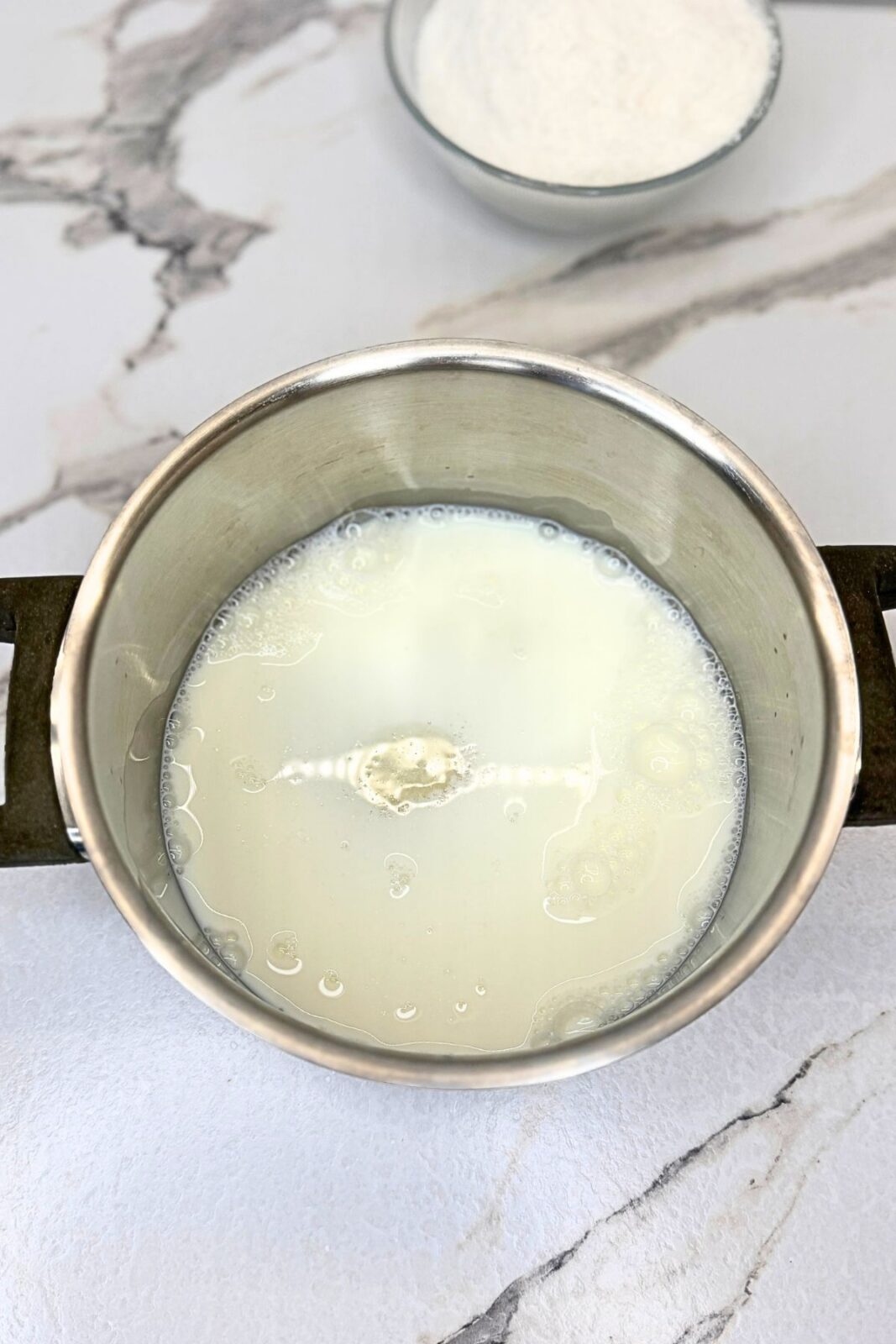 Milk mixture in a saucepan at the start of preparing the cream for Raffaello coconut balls.