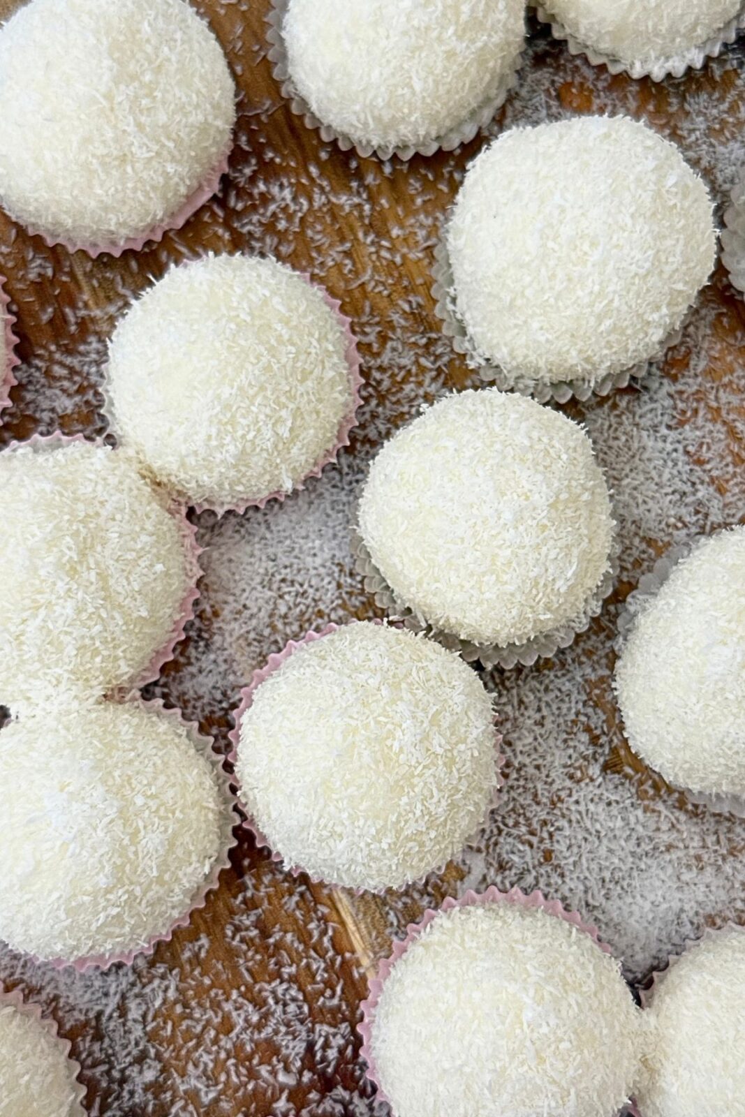 Hand holding a halved Raffaello coconut ball in a paper cup, revealing the creamy coconut filling and almond center.